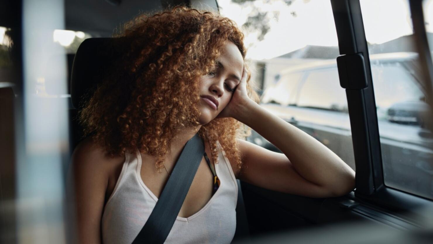 Young woman sleeping on backseat of car
