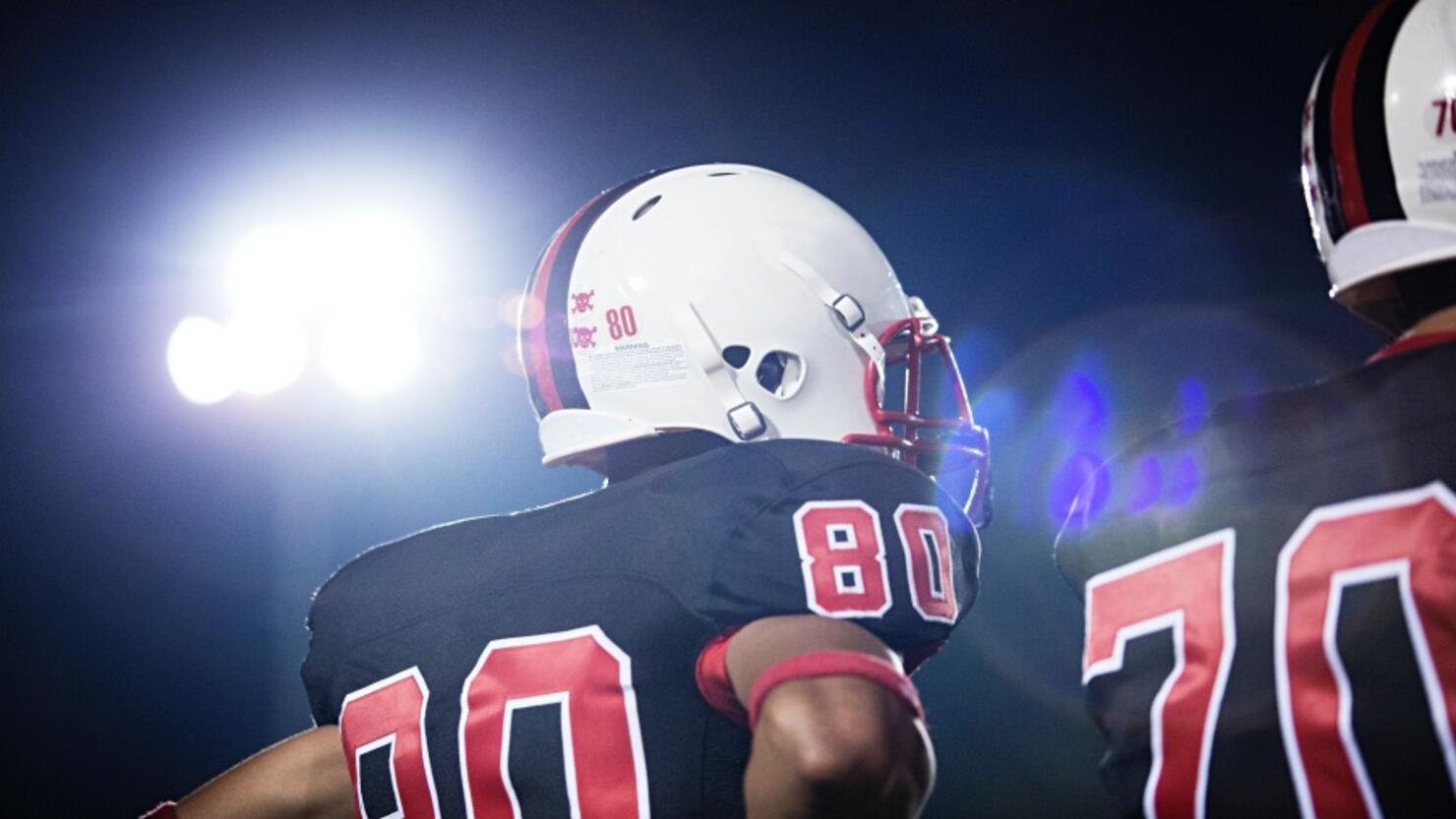 Low angle view of American football players against sky at night