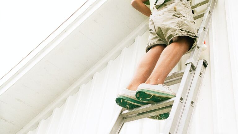 Man standing on ladder, low angle view