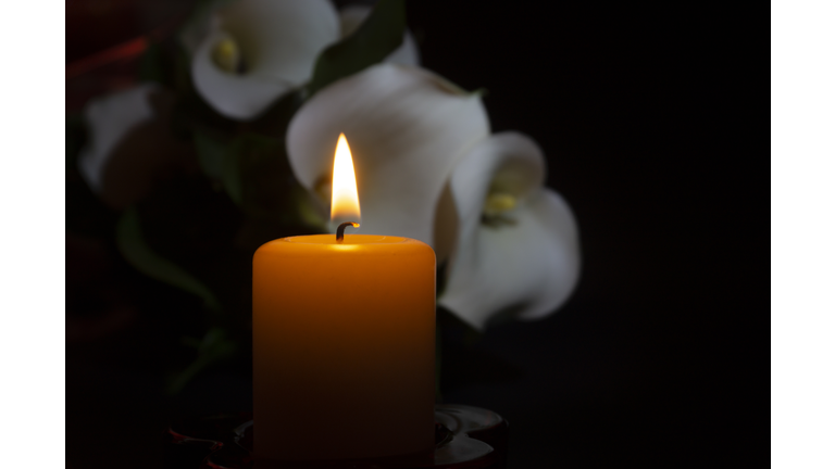 Close up of orange candle flame and lily flowers