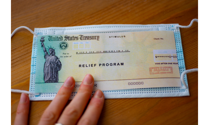 Stimulus relief program check over medical mask in hand.  Close up view
