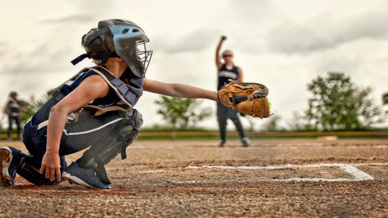 A softball catcher shown catching a pitch