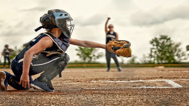 A softball catcher shown catching a pitch