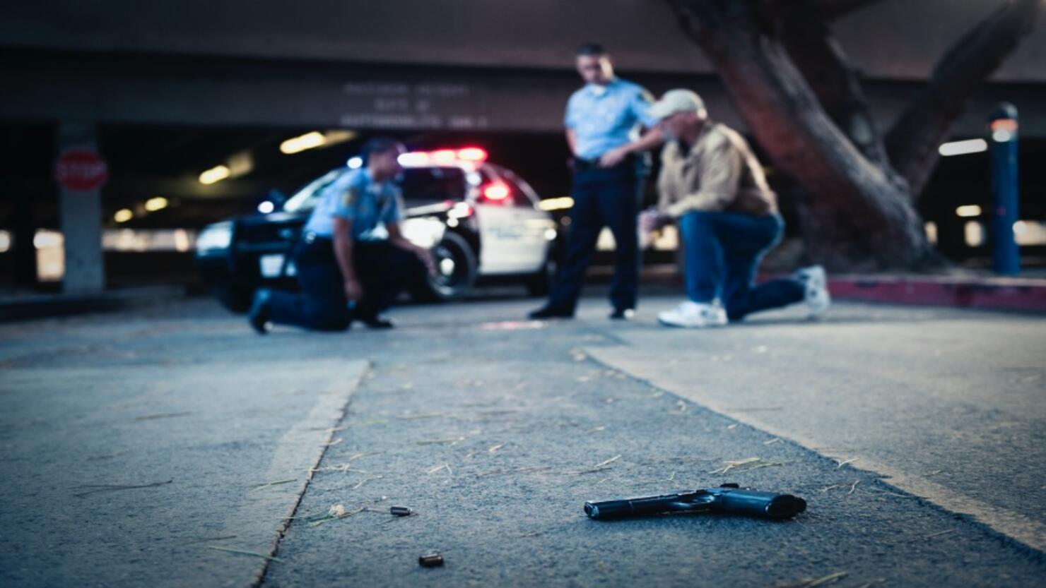 Police examining crime scene with gun on ground