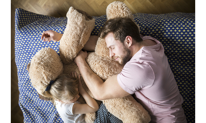 Father and daughter taking a nap, cuddling with teddy bear