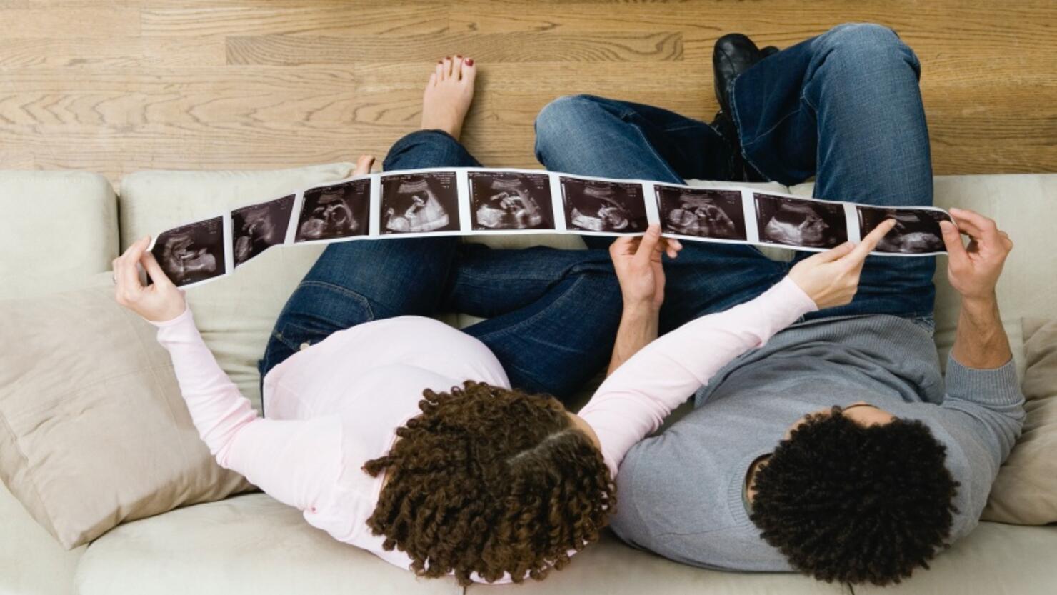 Pregnant African couple looking at ultrasound pictures