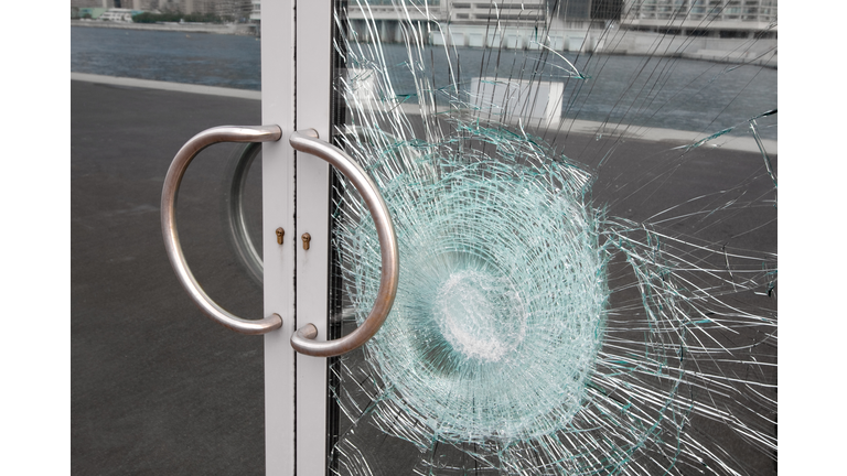 Broken window on business glass door shattered by vandalism