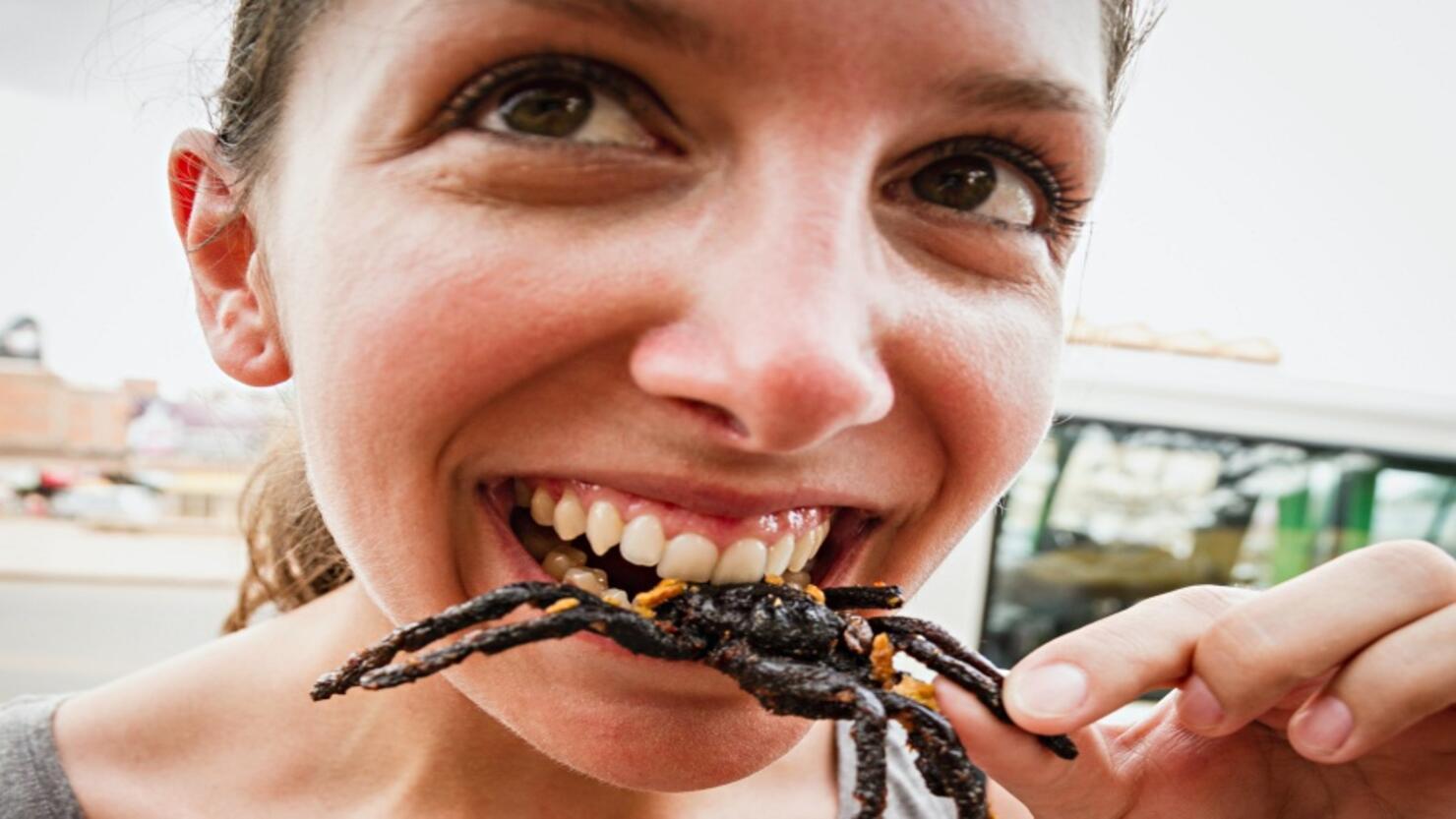 Cambodia, Young woman eating fried tarantula spiders