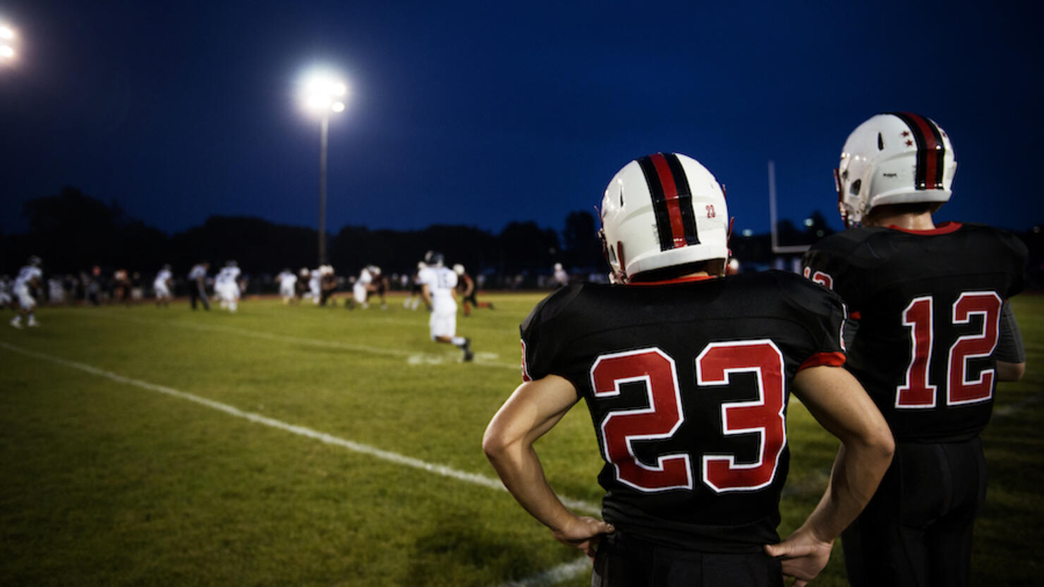 Rear view of American football players standing on Football field