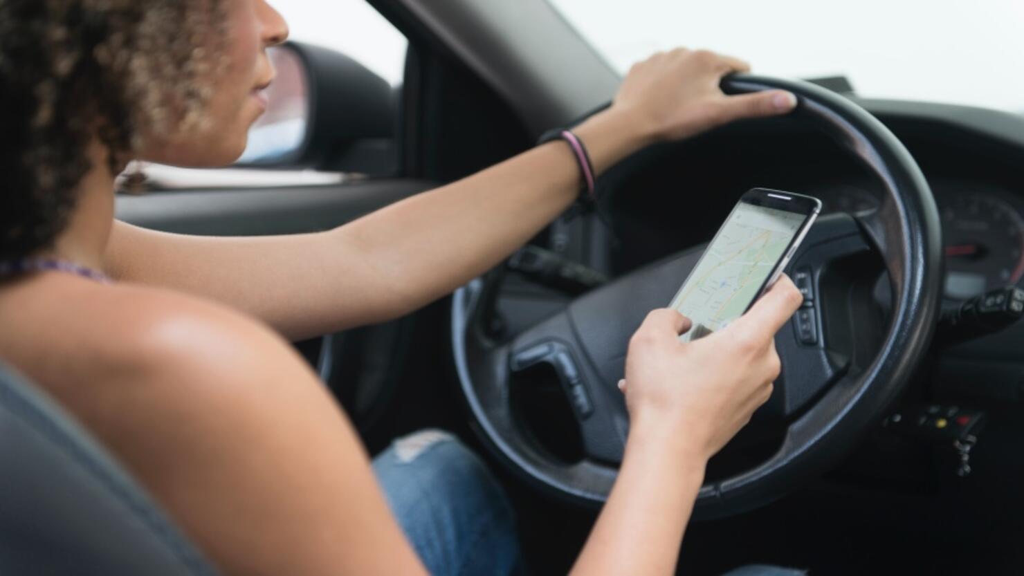 Young woman texting while driving car