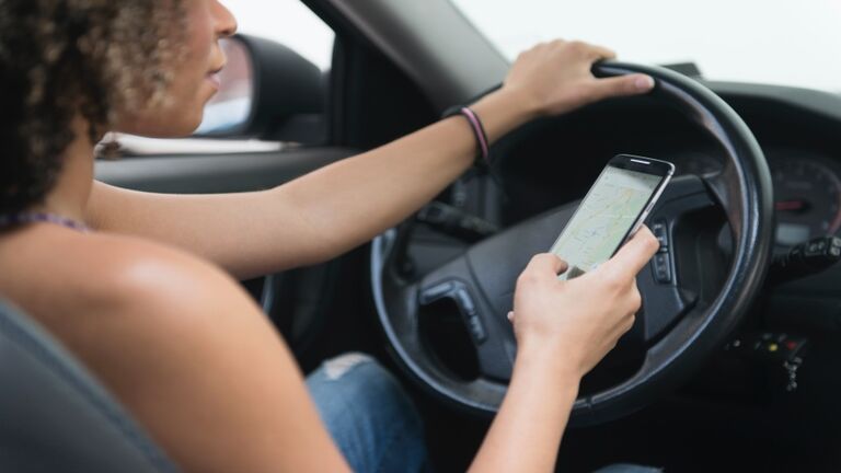 Young woman texting while driving car