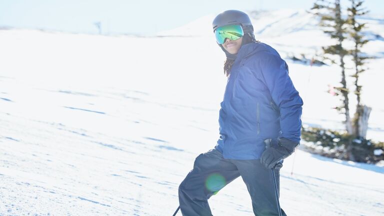 Portrait of man at top of ski slope while skiing on sunny winter afternoon