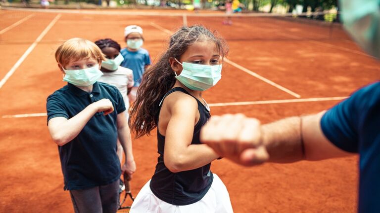 Kids elbow bumping their tennis instructor