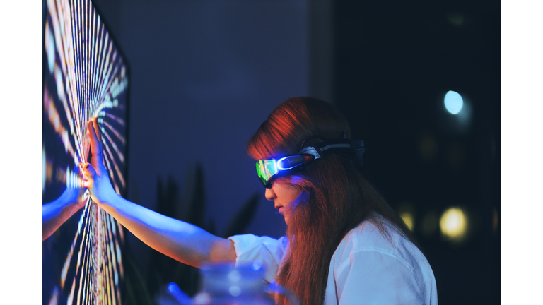 Young woman wearing augmented reality glasses touching screen with hands