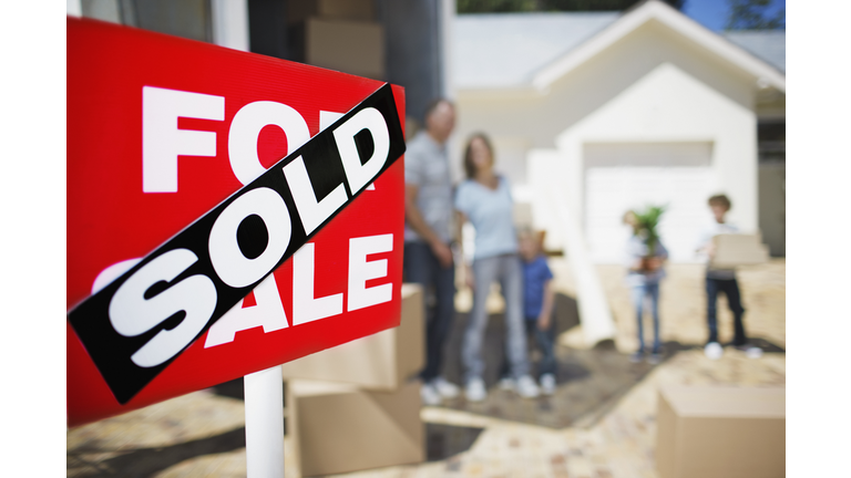 Sold sign on house with family in the background