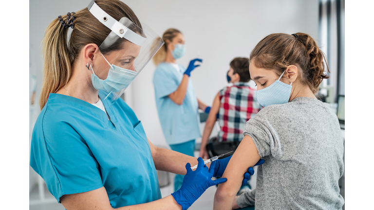 Doctor vaccinating girl. Injecting COVID-19 vaccine into patient's arm
