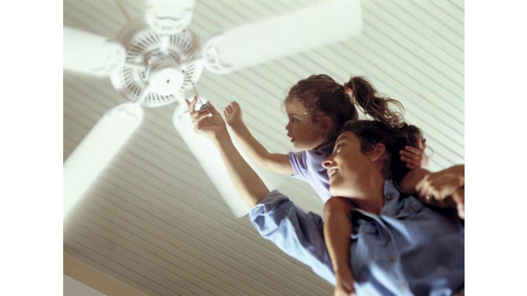 Mother and daughter turning on a celing fan