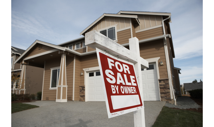 'For Sale' sign in front of house (focus on sign)