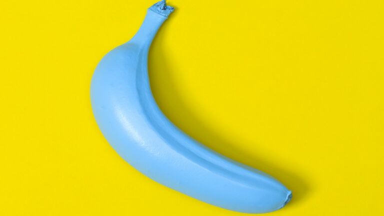 Close-Up Of Blue Banana Over Yellow Background