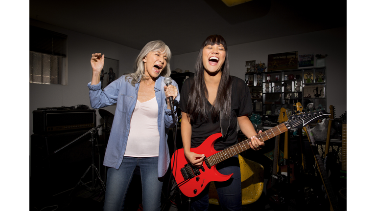 Mother and daughter playing music guitar in basement