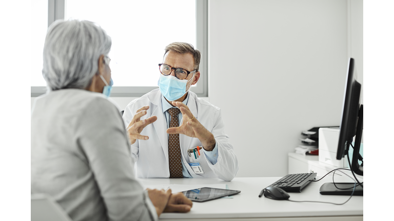 Male doctor discussing with woman during COVID-19