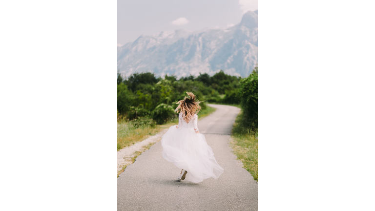 Rear View Of Bride Running On Road