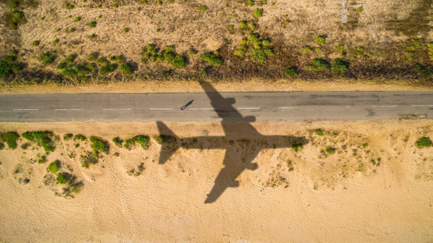 Aerial view airplane shadow and man on sunny road