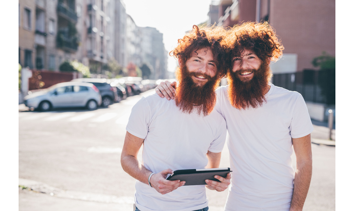 Portrait of young male hipster twins with red hair and beards on city street