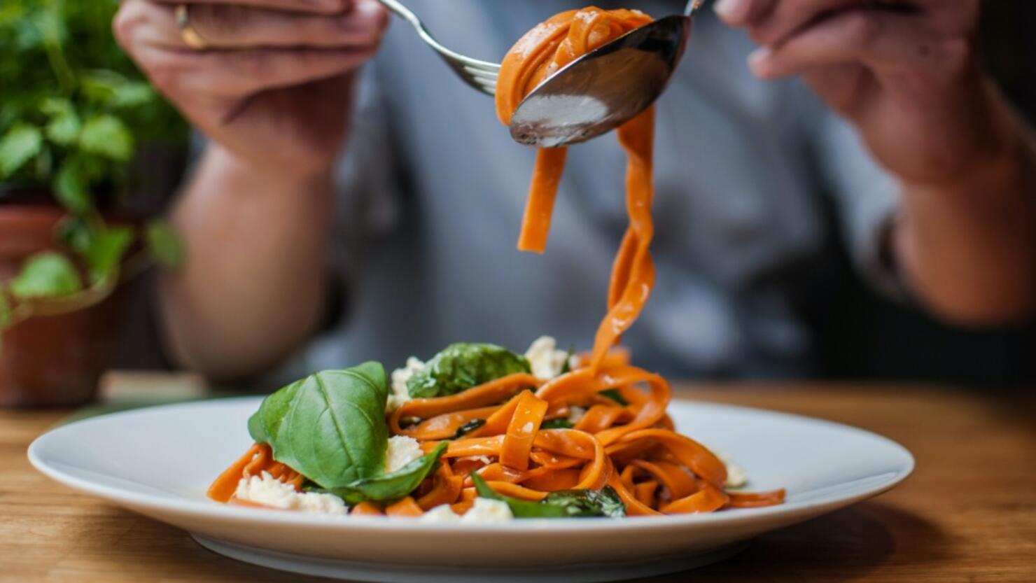 Midsection Of Man Having Pasta In Restaurant