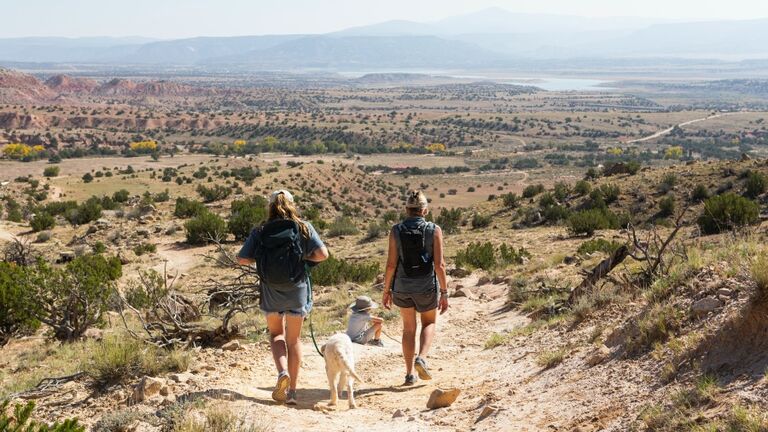 Three people, family hiking on a trail through a protected canyon landscape