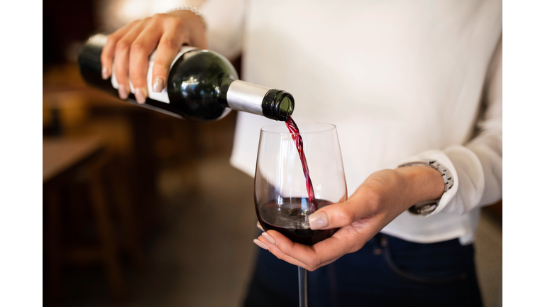 Woman serving red wine in a winery