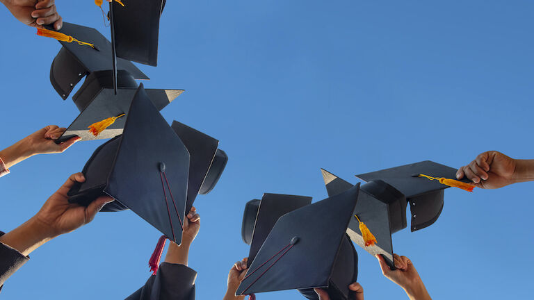 Low Angle View Of People Holding Cap Against Clear Sky