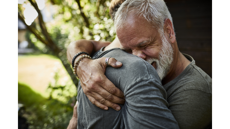 Two happy men embracing at garden shed