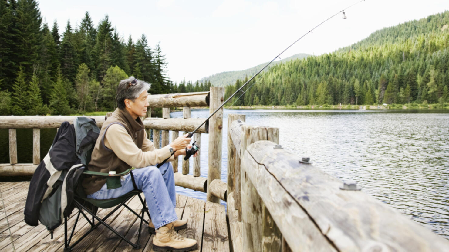 Download Man fishing at a serene lake with a high-quality fishing