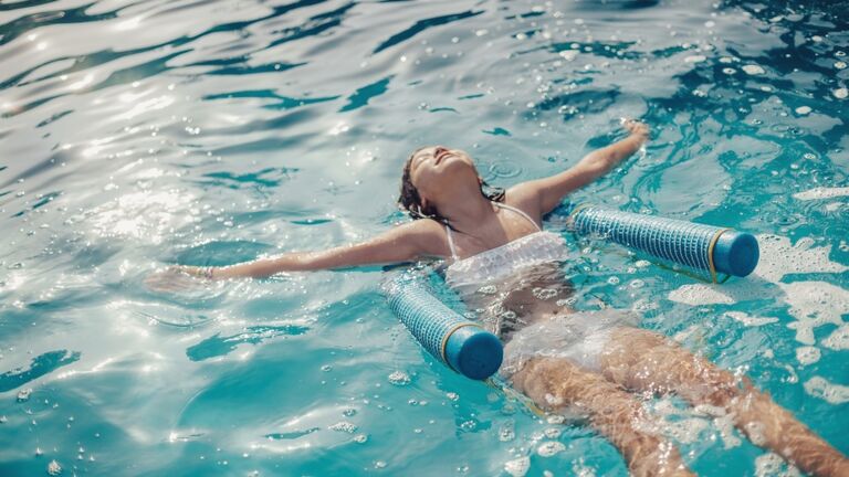 young brunette girl relaxing floating at pool