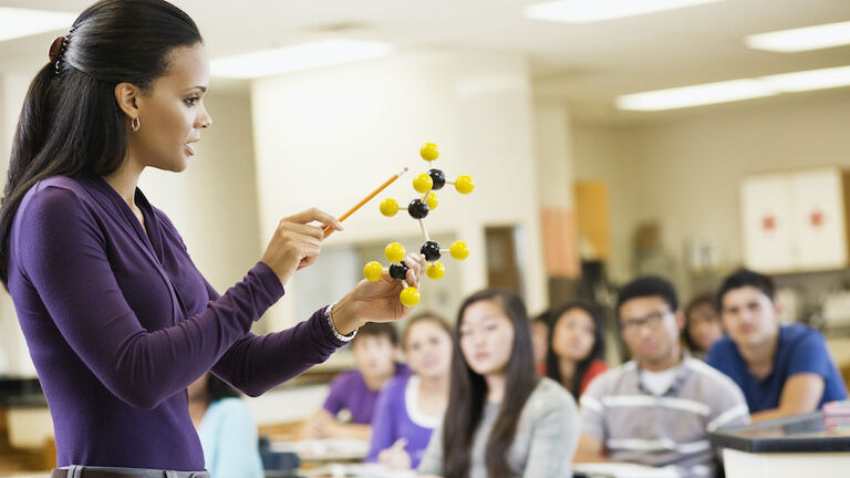 Teacher explaining chemistry model to classroom
