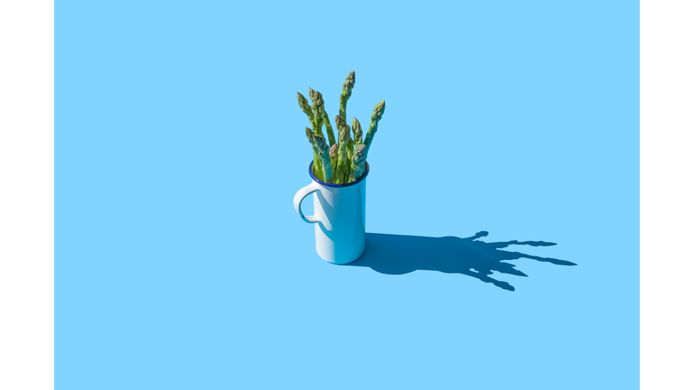 Asparagus in a white cup on the blue background