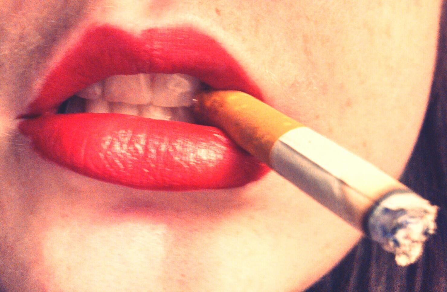 Close-Up Of Woman With Red Lipstick Holding Cigarette In Mouth