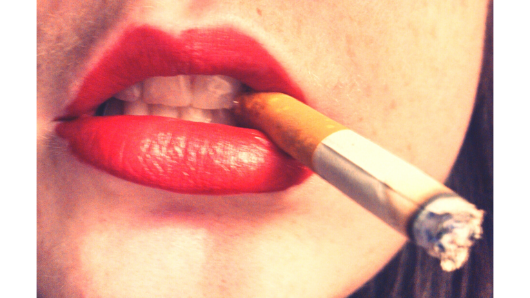Close-Up Of Woman With Red Lipstick Holding Cigarette In Mouth
