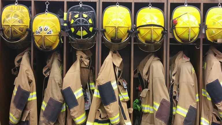 Firefighter Uniforms With Helmet Hanging In Rack