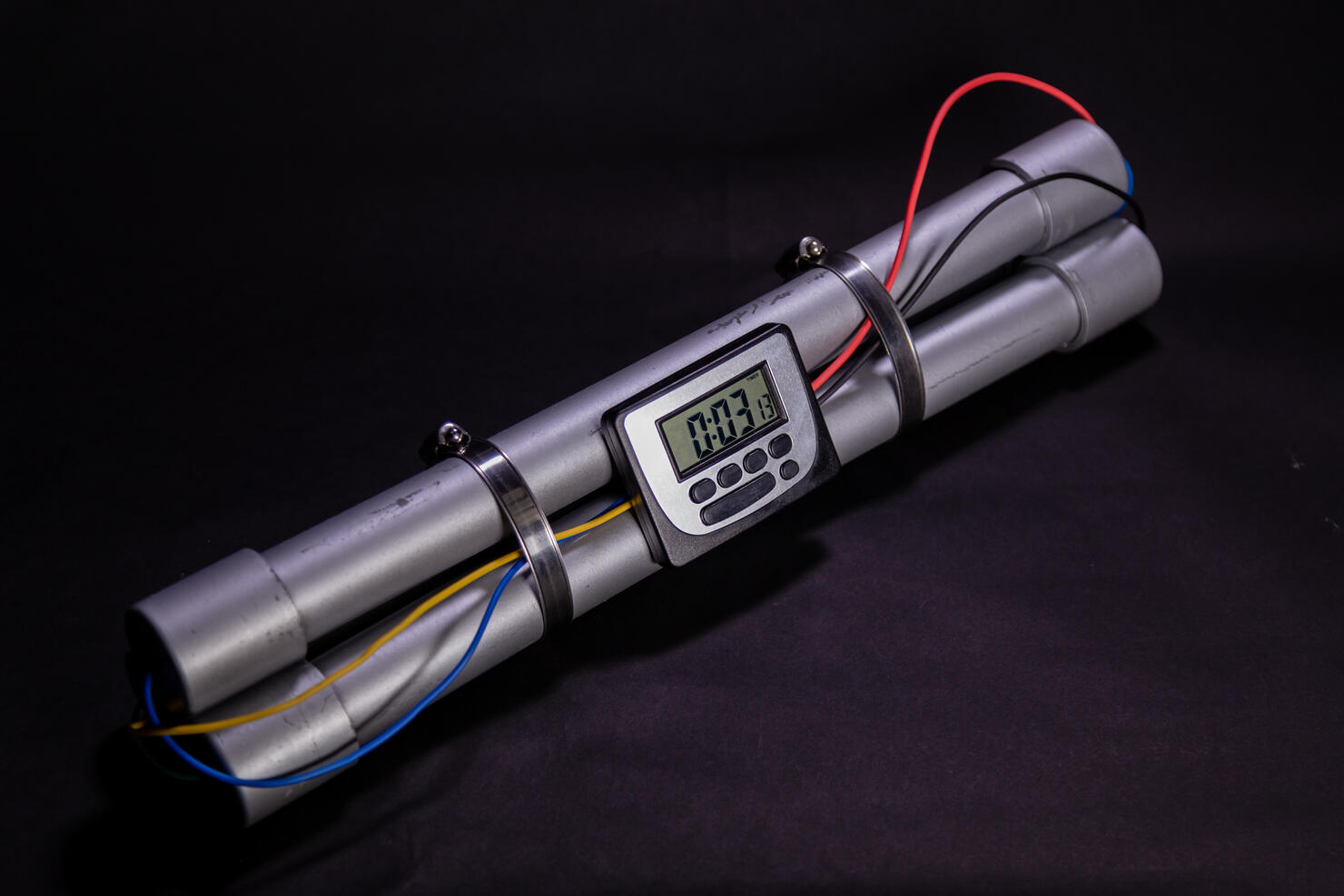 Pipe bomb with an clock timer to trigger detonation on black background