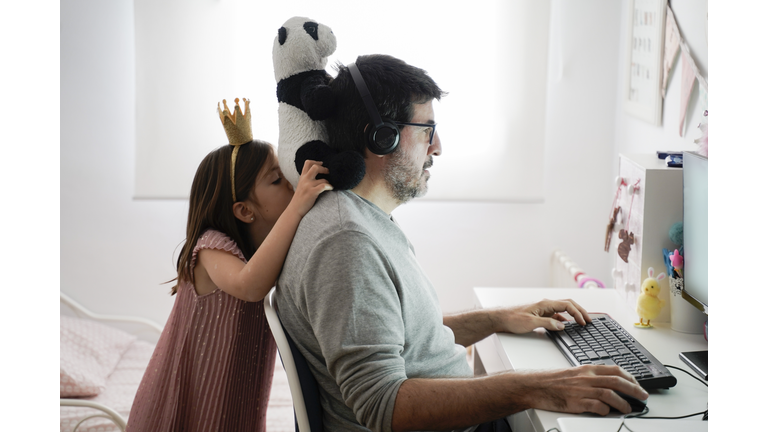 Man doing telework and a little girl playing around