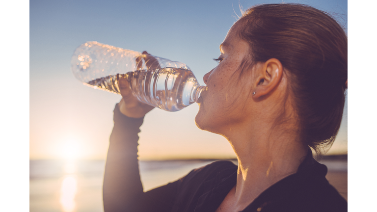 Woman drinking water seaside.