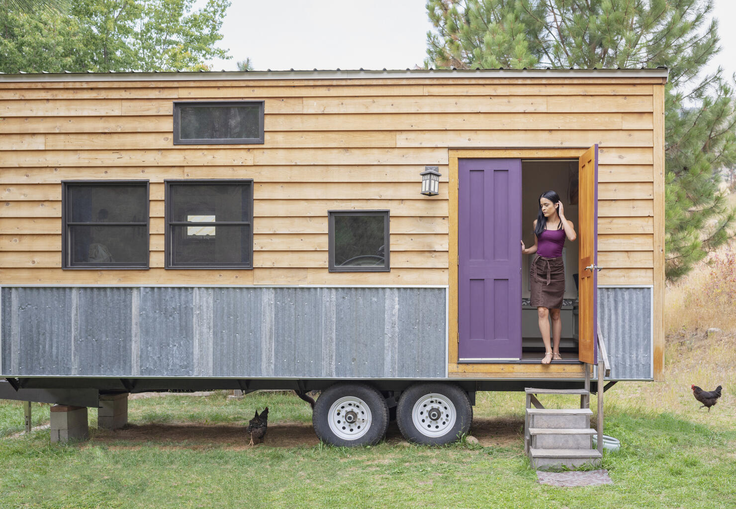 Young woman looking out door of her tiny house