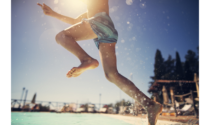 Little boy jumping into swimming pool