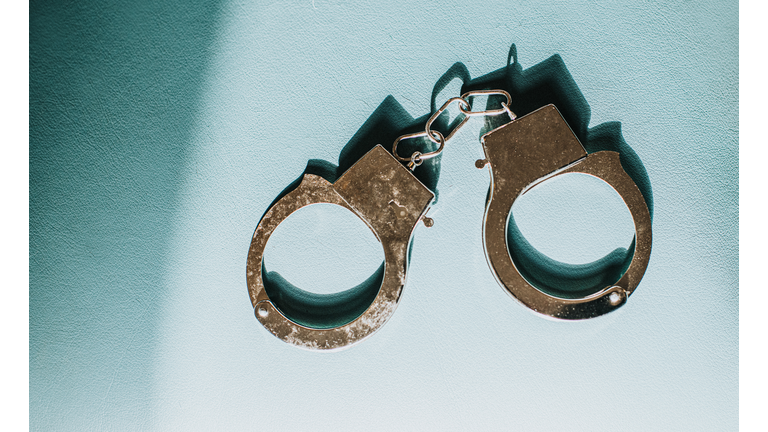 Simple Conceptual Image of Silver Handcuffs on Blue Surface