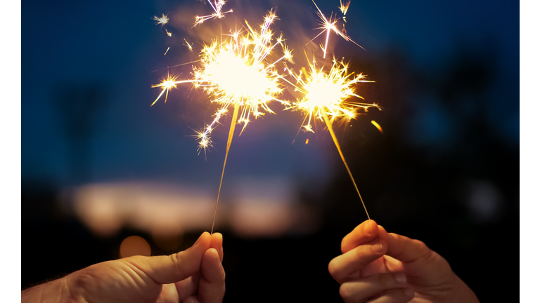 Hand Holding Firework Display At Night