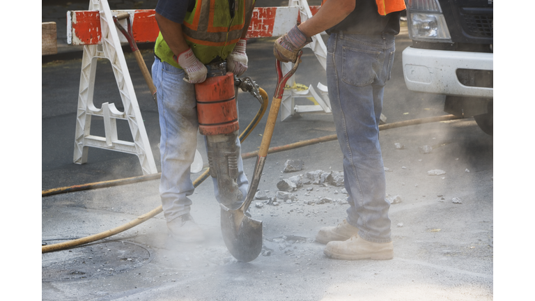 Construction workers using jackhammer and shovel