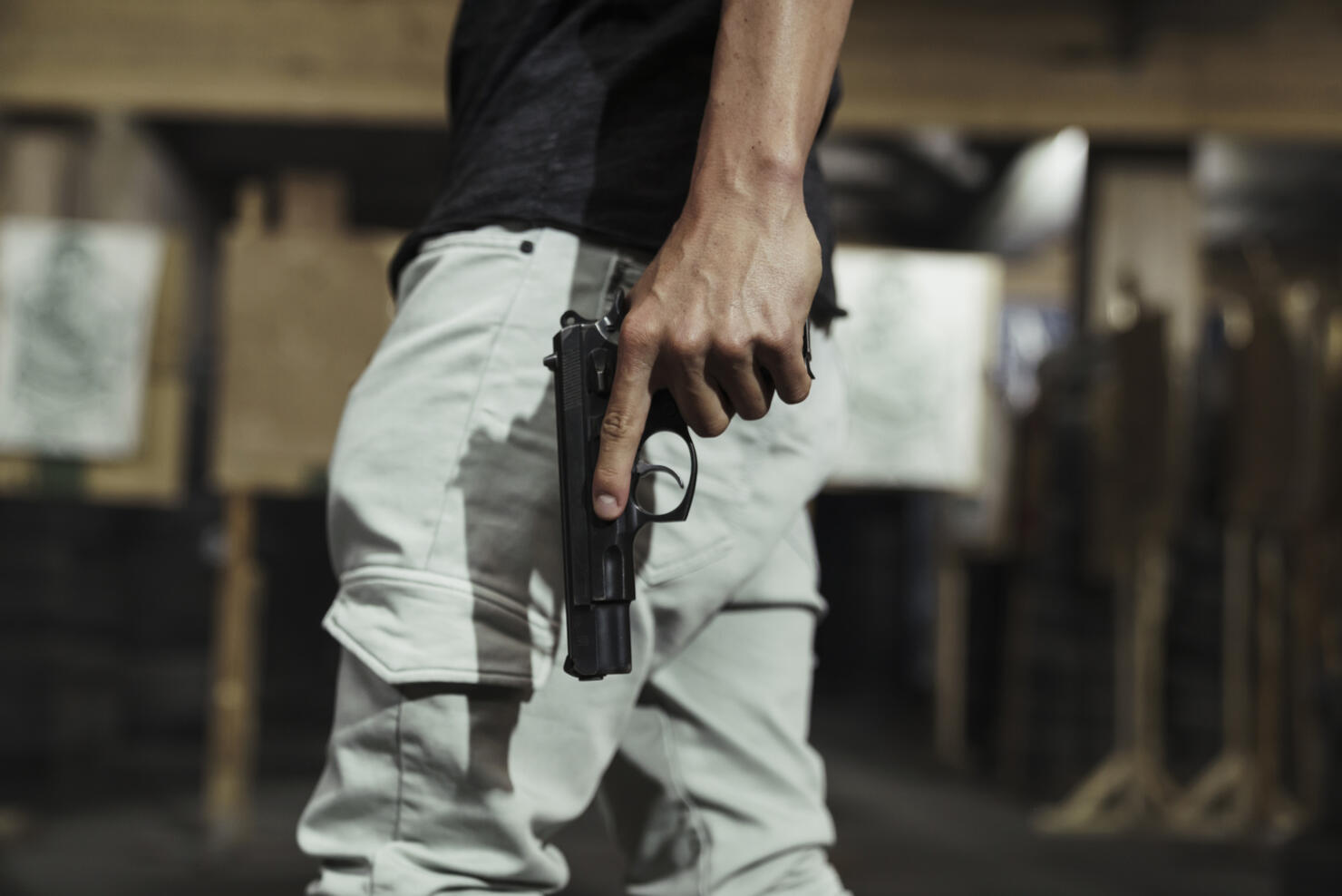 Close-up of man holding a pistol in an indoor shooting range