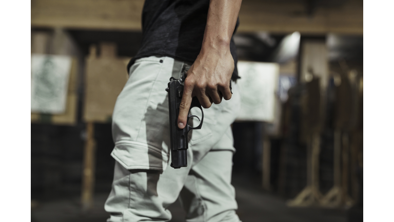 Close-up of man holding a pistol in an indoor shooting range